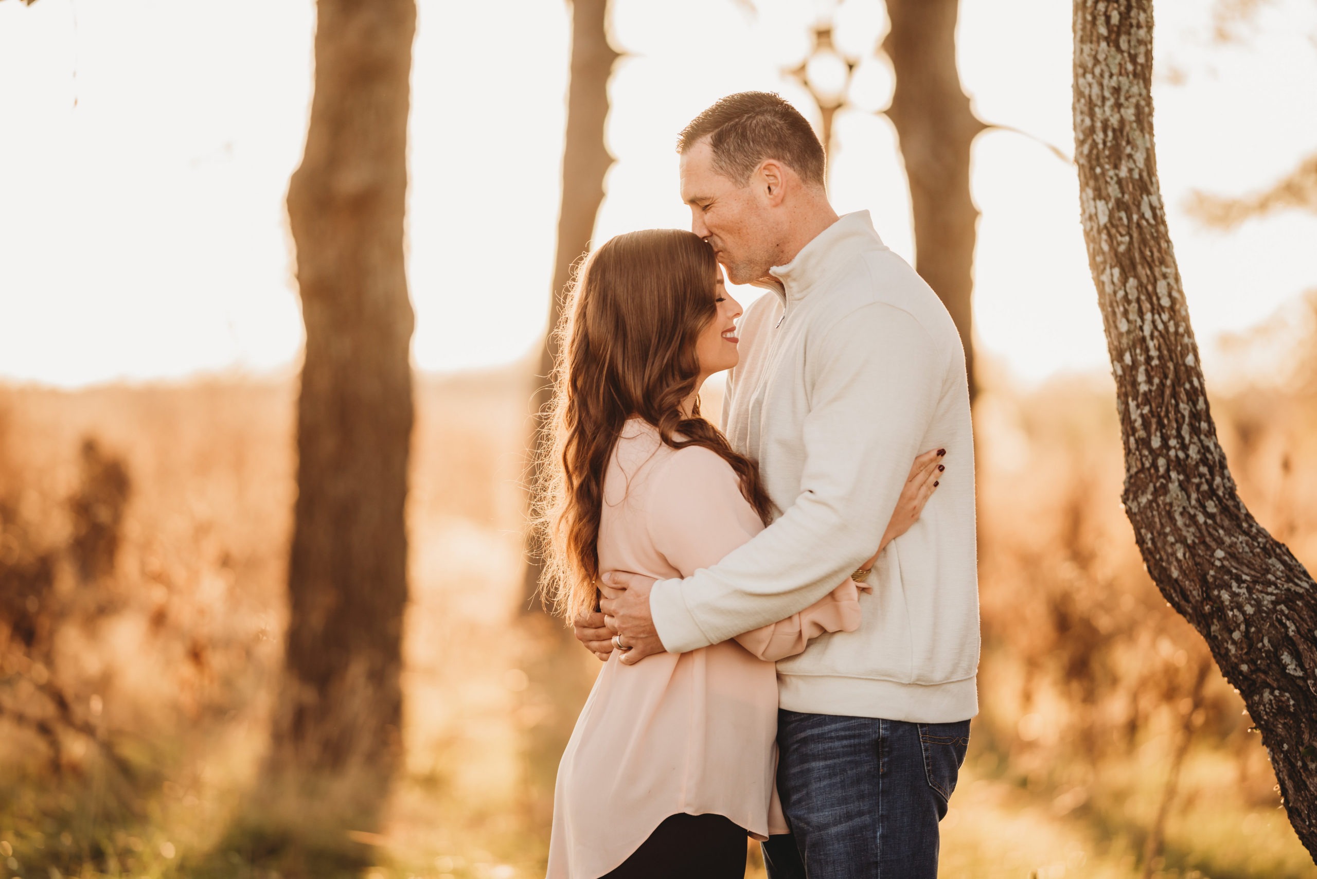 a woman with her husband as he kisses her on the forehead