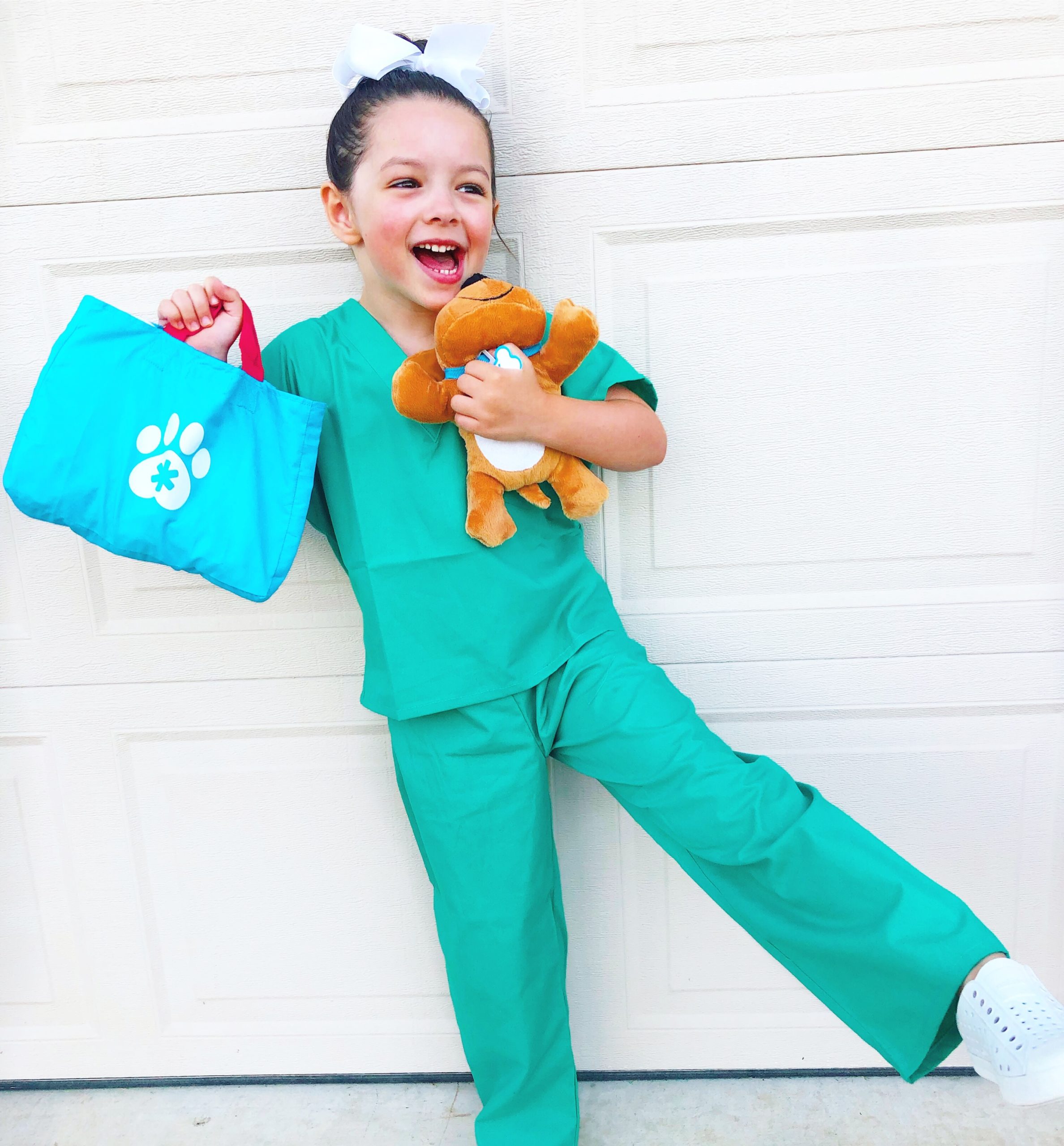 child dressed up as a vet holding a stuffed dog and vet kit